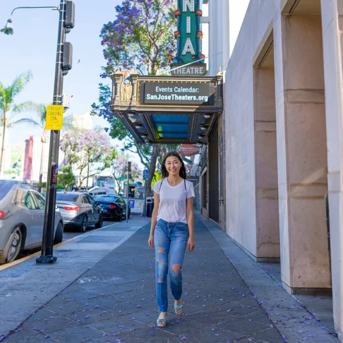 A female presenting individual in front of a San Jose, California theatre.